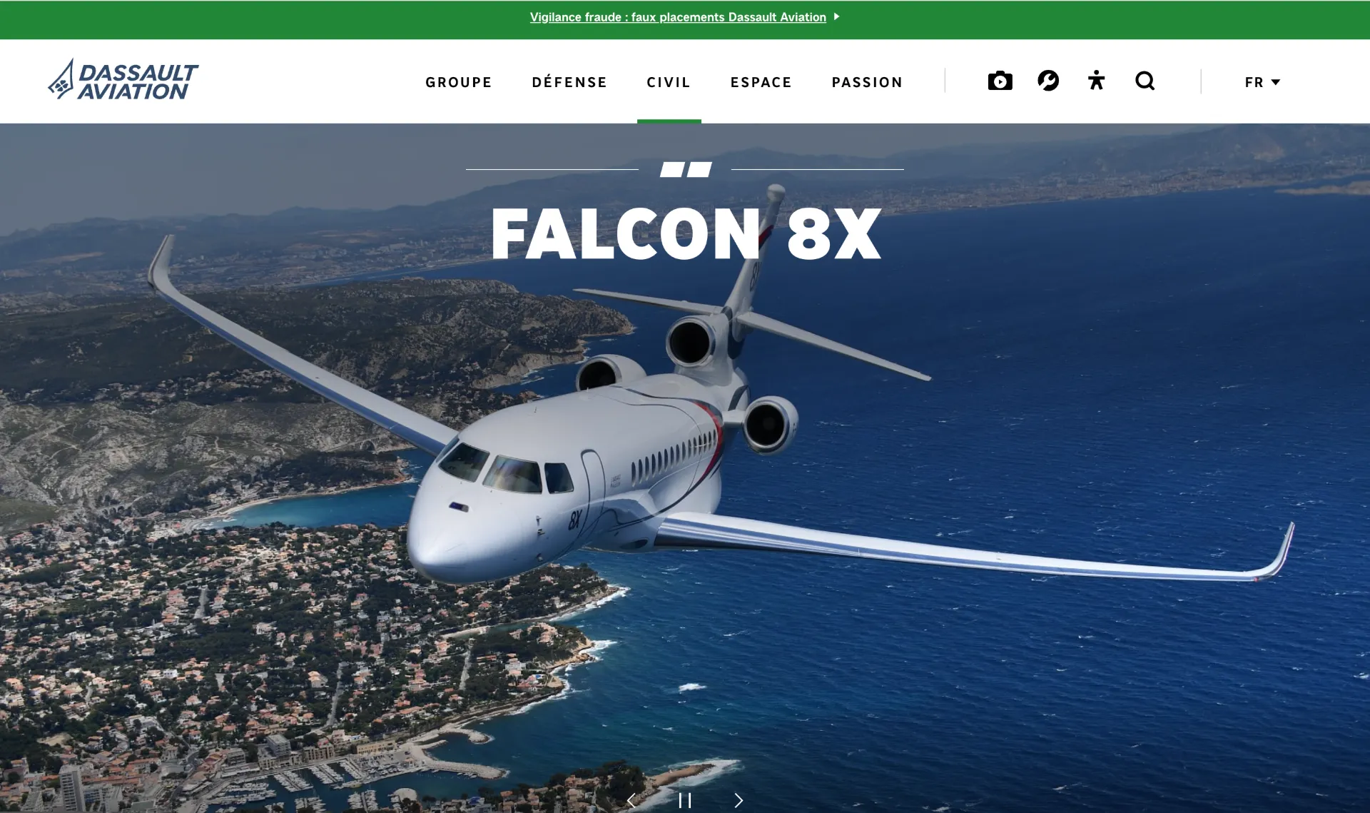 Avion Dassault Falcon 8X volant au-dessus d'une côte méditerranéenne.
